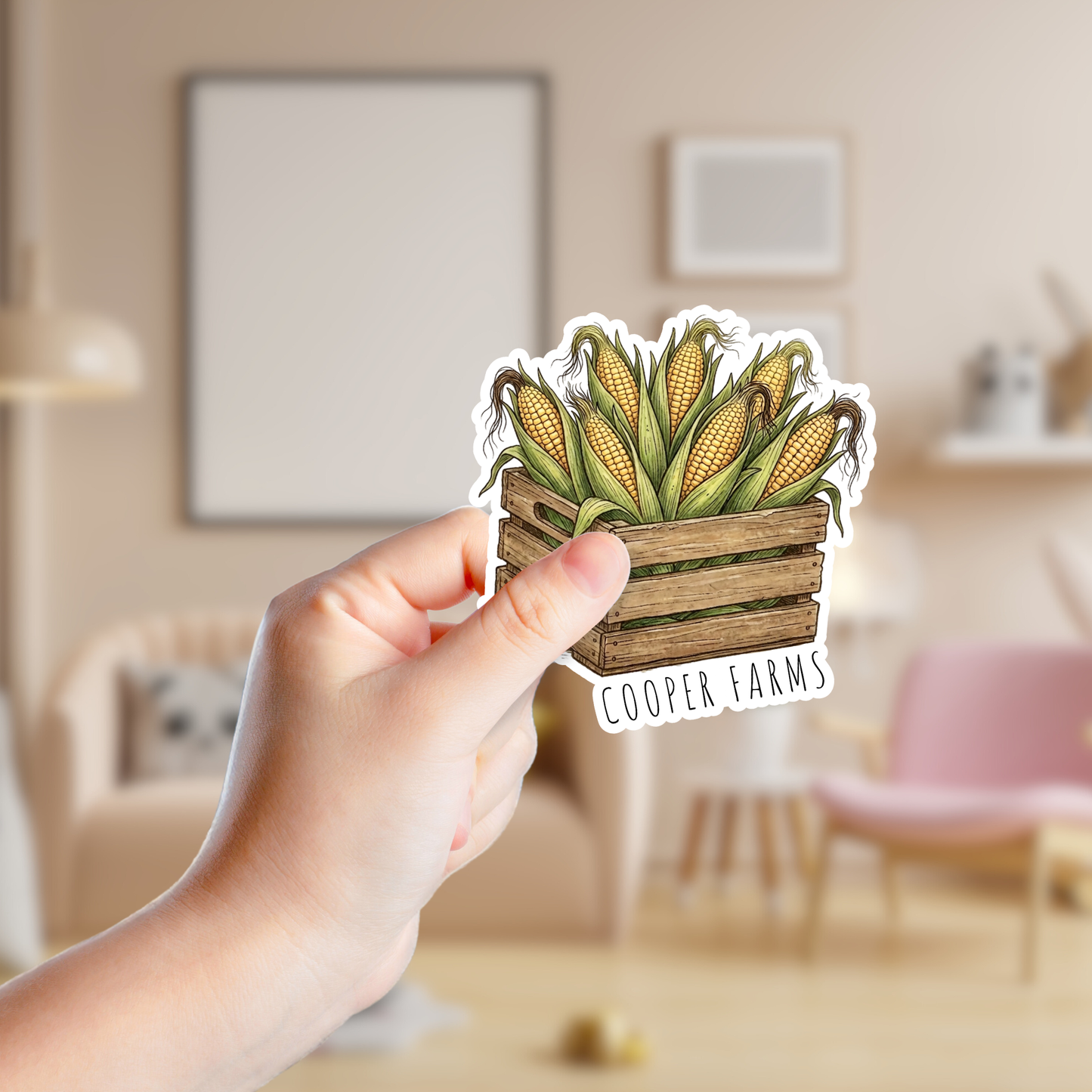 Hand holding a sticker of corn in a wooden crate with 'Cooper Farms' branding in a room.